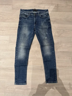 Black Rebel jeans - Säljer ett par blå slim jeans från Black Rebel med slitna detaljer och klassisk femficksdesign. Jeansen har normal midja, smal passform och är tillverkade i stretchig bomullsdenim för extra komfort. Perfekta för dig som gillar en avslappnad men ändå snygg look.