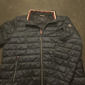 Tommy Hilfiger Jacka - Snygg och bekväm Tommy Hilfiger jacka i mörkblå färg. Lätt vadderad quiltad modell som passar perfekt för vår, höst och mild vinter. Jackan har hel dragkedja, hög krage och stilrena detaljer med Tommy Hilfiger-logga på bröstet och ärmen. Storlek: XXL Skick: Bra skick, normalt använd, inga hål eller fläckar Färg: Mörkblå En tidlös och praktisk jacka som passar både till vardag och mer uppklädda tillfällen. Skicka gärna meddelande vid frågor! 😊