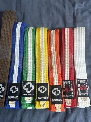 Ingen väst på bilden - Bilden visar inga västar utan olika färgade bälten från Budo-Nord, troligen för kampsport som karate eller judo.