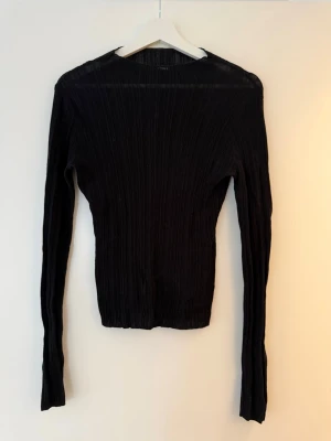 Svart ribbad tröja från BikBok - Säljer en svart ribbad långärmad tröja från BikBok i storlek L. Tröjan har en tight passform och är tillverkad i ett stretchigt material som sitter snyggt på kroppen. Perfekt basplagg till garderoben! Eller till fest. Känns som M-L