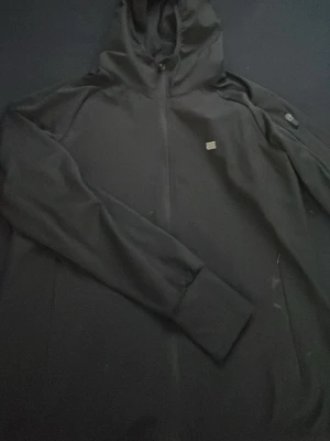 Svart vindjacka med huva - Säljer en svart vindjacka från Björn Borg med hel dragkedja och huva. Jackan har en stilren look med diskret logga på bröstet och långa ärmar. Perfekt för dig som vill ha en enkel och sportig jacka till vardags.