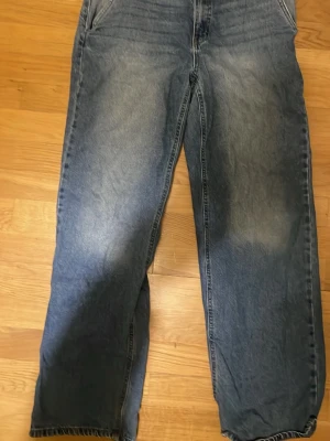 Blå baggy jeans från LMTD S/M - Säljer ett par blå baggy jeans från LMTD i storlek S/M. Jeansen har en loose passform med raka ben och klassisk femficksdesign. Materialet är slitstarkt jeans och färgen är tvättad blå med lite ljusare partier framtill och baktill.