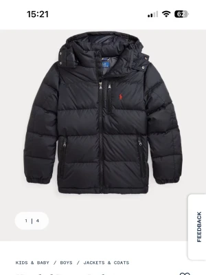 Svart pufferjacka från Polo Ralph Lauren - Säljer en svart pufferjacka från Polo Ralph Lauren med röd broderad logga på bröstet. Jackan har huva, flera dragkedjefickor och är quiltad för extra värme. Perfekt för kalla dagar och har en clean, sportig look. Stl 150, 10-12år.