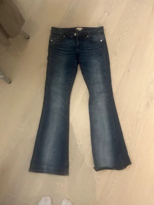 Blå bootcut jeans med broderad ficka - Säljer ett par mörkblå bootcut jeans med snygg slitning och broderad bakficka i röd, lågmodjade❤️