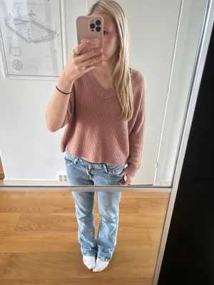 Rosa stickad tröja från NA-KD - Mysig stickad tröja från NA-KD i en dämpad rosa nyans. Tröjan har en avslappnad passform, v-ringad hals och långa ärmar. Perfekt att slänga på sig till jeans för en chill look. Den är oversized så skulle inte säga den är xs 