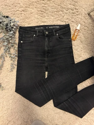 Svarta skinny jeans med hög midja - Säljer ett par svarta skinny jeans med hög midja. Jeansen har klassisk femficksdesign, smala ben och är tillverkade i stretchigt jeansmaterial för en tajt passform. Perfekta till sneakers eller boots.