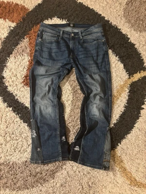 Bootcut Jeans DIY - Laid out liggandes.        •	Längd: 98 cm 	•	Midja: 44 cm 	•	Innerbenslängd: 26 cm 	•	Nedre bredd (vid benslutet): 25 cm  Kondition: 8,5/10  Fraktar samma dag eller dagen efter✅   swag rap streetwear baggy vintage skate hiphop y2k affliction archive underground avant garde japan style OG 2000s flared washed affliction jeans drip oldmoney denim