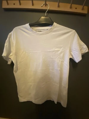 Vit basic t-shirt från C&A - En klassisk vit t-shirt från C&A i mjuk bomull. Modellen är enkel med rund halsringning och korta ärmar, perfekt till jeans eller shorts. Snygg och stilren utan tryck eller mönster, passar dig som gillar en clean look. Skick till mig!