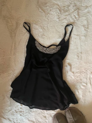 Svart linnetopp med strassdetaljer - Snyggt festligt linne / topp som har dit-sydda silvriga diamanter/pärlor vid bröstet. Från märket Siluette storlek L. 🪩