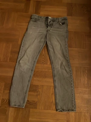 Grå loose fit jeans Jack & Jones - Säljer ett par grå loose fit jeans från Jack & Jones, modell Chris. Klassisk femficksdesign, raka ben och knappgylf. Jeansen är i bomull och har en avslappnad passform som ger en chill vibe till outfiten.