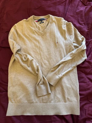 Beige v-ringad tröja Tommy Hilfiger - Säljer en beige/brun tröja från Tommy Hilfiger i storlek L. Tillverkad i en mjuk  kashmir. 
