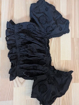 Svart broderad blus från NA-KD - Säljer en svart blus från NA-KD i storlek 34. Toppen har korta puffärmar, broderade detaljer och volangkant. Kort i modellen. Materialet är lätt och luftig bomull, perfekt för varmare dagar. Söt och trendig modell med elastiska partier för skön passform.                                                                       Pris kan diskuteras vid smidigt köp 😊.                        Köparen står för frakt! 