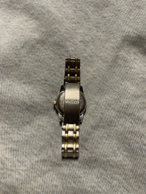 Certina klocka i silver och guld - Snygg Certina armbandsur med klassisk rund urtavla i silver och gulddetaljer. Länken är tvåfärgad i silver och guld. Stilren design som passar till allt, med metallarmband och guldfärgad krona. Inget slitage och funger utmärkt!