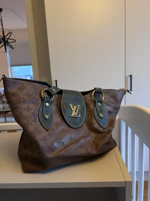 Vintage väska  - Skinn/läder väska. Väskan har mörkgröna detaljer, guldiga metalldelar och dragkedja upptill. Insidan är beige med flera fack och dragkedjor för smart förvaring.  Små skavanker se bilder bla en dragkedja inuti som saknas men inget som stör :)