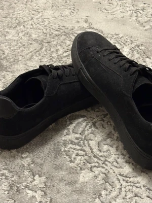 Svarta Mocca skor  - Snygga helsvarta finskor i mocca som nya, skorna har snörning och är tillverkade i mocka med detaljer i syntet vid hälen. Perfekta för dig som gillar stilrena och finskor med en modern vibe, pris kan diskuteras vid snabb affär.