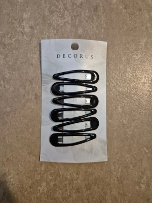 Hårspänne - Snygg svart hårspänne från Decorus i klassisk design. Hårspännen har en enkel och stilren look utan mönster eller extra detaljer. Oöppnad. Köpte fel.