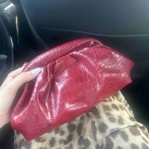 Röd clutch väska - Snöret går att ta av och på så även en clutch bag samtidigt! snygg röd kuvertväska med croco-mönster. Den känns lite ”slö” att få upp!