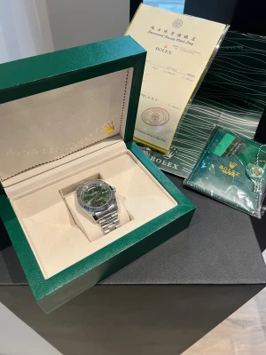 Rolex Day-Date grön urtavla stål - Säljer en riktigt snygg Rolex Day-Date med grön urtavla och klassisk räfflad bezel. Klockan har en länk i polerat stål och dag- och datumvisning. Kommer i originalbox med certifikat och tillbehör. Perfekt för dig som vill sticka ut med stil.