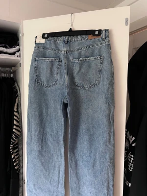 Blå ripped wide jeans strl 38 - Säljer ett par ljusblå jeans med raka ben och slitna hål över knäna. Medelhög midja. Perfekta för en avslappnad och trendig look. Önskar du veta exakta mått? Tveka inte att höra av dig!