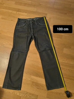 Mörkblå jeans med knappar bak - Snygga mörkblå  jeans med raka ben och coola detaljer som dubbla knappar och fickor med lock bak. Klassisk femficksdesign fram och slitningar för en avslappnad vibe. Passar dig som gillar street och casual stil.