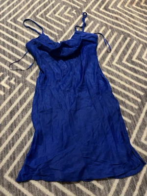 Kornblå kort slipklänning med tunna band - Supersnygg kornblå slipklänning från Bershka med tunna axelband och lätt draperad urringning. Klänningen är kort och har en figurnära passform, perfekt för sommarkvällar. Materialet är satin.