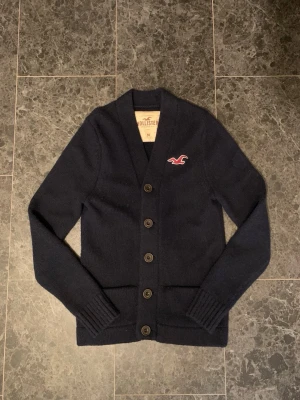 Hollister Cardigan - Tja! Säljer en fet Hollister cardigan i färgen mörkblå. Som är i toppskick! Storleken är M men sitter mer som S. Bara att höra av sig vid eventuella frågor!