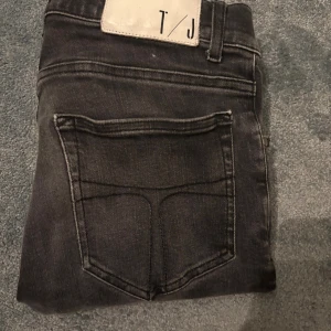 W30 L30 Svarta slim jeans från T/J (Style:evolve) - Säljer ett par svarta slim jeans från T/J med klassisk femficksdesign och snyggt tvättad finish. Jeansen är i bra skick och är i storlek 30 30. Levererar inom 1 dag!🚚