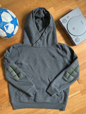 Mörkgrå hoodie med vadderade armbågar - Säljer min G-Star tröja 🔗 Säljer nu min unika hoodie från G-Star RAW (modell: Aero Patched On Pocket Sweater).   Tröjan har en snygg industriell look med sina  karaktäristiska vadderade armbågslappar och en modern omlottkrage vid huvan. 🧱   Detaljer & Mått: • Storlek: står L men passar mer S (S) • Längd: 64 cm 📏 • Bredd: 50 cm • Skick: Mycket fint skick med välbevarade detaljer och muddar.  Övrig info: Jag packar alltid varan noggrant och skickar den snabbt efter avslutad affär! 📦⚡