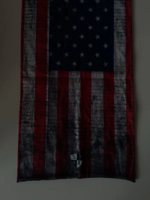 Sjal med amerikanska flaggan - Cool sjal med amerikanska flaggans motiv i rött, vitt och blått. Trycket har en lite sliten vintage-look. Perfekt accessoar för att sticka ut.