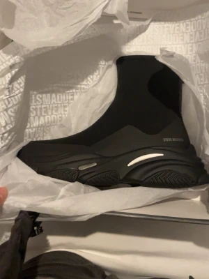 Svarta Chelsea boots Steve Madden - Chunky svarta Chelsea boots från Steve Madden med elastiska partier på sidorna och kraftig platt sula. Snygg, modern siluett med diskret logga på sidan. Perfekta för dig som gillar streetstyle och vill ha ett statement-plagg i garderoben.