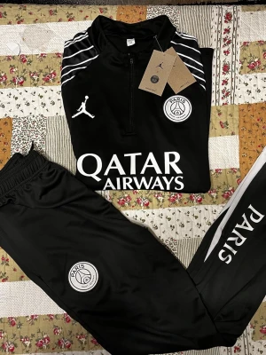Psg set  - Säljer ett svart PSG träningsset från Jordan x Nike, bestående av långärmad tröja med halv dragkedja och matchande byxor. Setet har vita detaljer, PSG-logga, Jordan-logga och Qatar Airways-tryck. Perfekt för fotbollsträning eller chill. Materialet är mjukt och stretchigt. Helt ny 