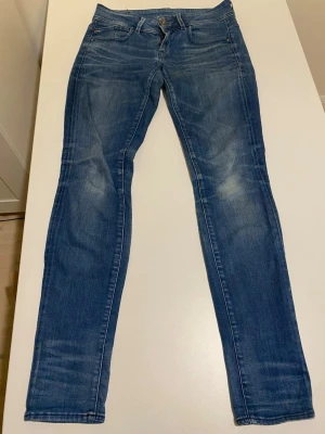 G-star raw jeans L32 W29 - Säljer ett par klassiska blå skinny jeans från G-Star RAW. Jeansen har fem fickor, normal midja och snygga slitningar på låren och knäna för en cool look. Tillverkade i mjukt denimtyg som sitter tight hela vägen ner.