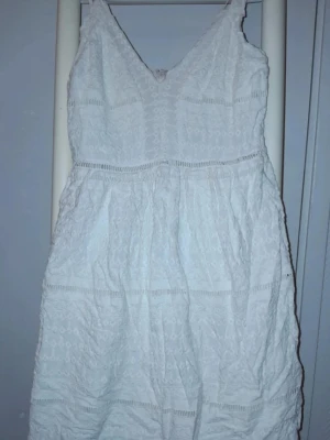 Vit klänning med v-ringning - Söt vit klänning med v-ringning och tunna axelband. Perfekt för sommarens alla tillfällen.