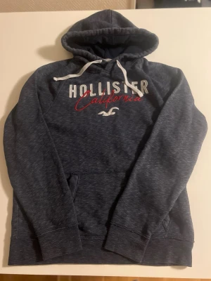 Hollister California hoodie grå/mörkblå  - Hollister California hoodie i grå/mörkblå färg. Riktig bra skick inga fel. Storlek L pris 238 kr kolla även mina andra annonser för mer 😃