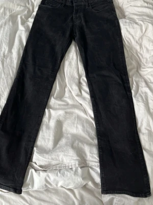 Svarta bootcut jeans från Levi's - Snygga svarta jeans från Levi's med klassisk femficksdesign och bootcut passform. Jeansen har normal midja och raka ben som blir något vidare nedtill. Tillverkade i slitstarkt denimtyg som ger en tidlös look.