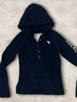 Abercrombie & Fitch hoodie XS - En väldigt snygg Abercrombie & fitch tröja i färgen mörkblå med vita detaljer! Storlek XS. Bra skick! 😀
