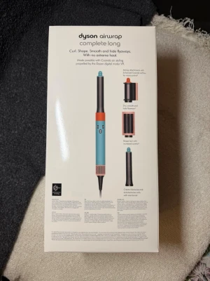 Dyson Airwrap Complete Long blå/orange - Dyson Airwrap Complete Long i blå och orange, ett multifunktionellt stylingverktyg med flera tillbehör för att locka, forma och släta ut håret utan extrem värme. Drivs av Dyson digital motor V9 och passar olika hårtyper. Levereras med sex olika stylingtillbehör. Den är helt oöppnad , finns att hämta i Göteborg eller frakt via PostNord 