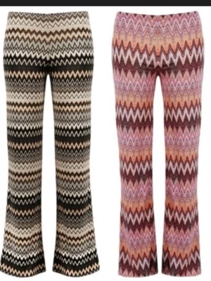 Rosa mönstrade bootcut orrebyxor - Snygga bootcut med färgglatt zigzag-mönster i rosa, svart, beige och orange toner. Byxorna har hög midja och är tillverkade i ett stretchigt material som ger en skön passform. Perfekta för dig som vill sticka ut med din stil.