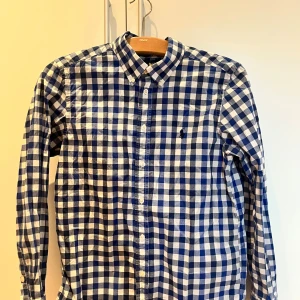 Rutig skjorta från Ralph Lauren  - Blåvit rutig skjorta från Raffe. Väldigt snygg att använda som ett lager med T-shirt under. Storleken är 14-16 år och skulle kunnas jämföras med en XS. Priset är fast så skicka inga prisförslag under 250kr! Har ni en fråga är det bara och höra av sig✌️