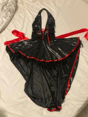 vampy klänning - cool halterneck vampyrisk klänning som är längre bak än fram. har snörning fram samt röda band att knyta runt midjan. perfekt som utklädnad eller till festtillfällen. har några lösa trådar men är annars i bra skick.
