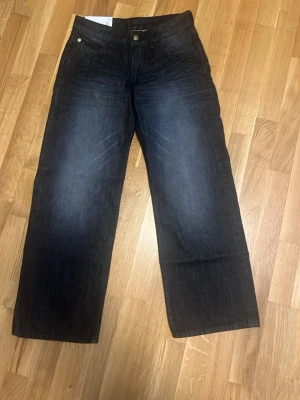 Weekday low waist baggy jeans - Säljer ett par mörkblå Weekday 569 jeans med bred passform och raka ben (low waist). Klassisk femficksmodell med snygga detaljer och Weekdays patch bak. Perfekta för dig som gillar en loose och avslappnad stil. 