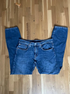 Blåa jeans ifrån Levi's med modell 502  - Säljer ett par Fina Levis 502 i fint skick. 5 ficks design i blå färg! Bra skick! Liten sliting i de sydda där bak men inget man tänker på! Hör av er vid eventuella frågor! 😊
