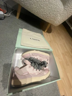 Lanvin rosa sneakers med chunky sula - Säljer ett par snygga Lanvin sneakers i ljusrosa med chunky beige sula och svartvita snören. Skorna har en modern, sportig look och är tillverkade i en mix av skinn och textil. Kommer i originalkartong och dustbag.