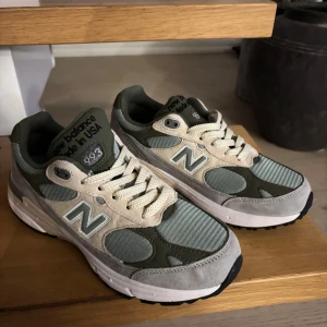 New Balance 993 grön/beige sneakers - Snygga New Balance 993 sneakers i en mix av grönt, beige och grått. Skorna har klassisk N-logga på sidan, meshpaneler för extra ventilation och detaljer i mocka. Platt sula och rund tå för skön komfort. Perfekta för dig som gillar stilrena och sportiga sneakers. Fick de i present men de va för stora.
