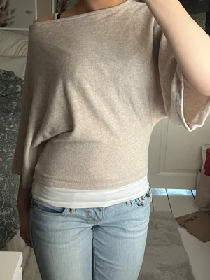 Jätteskön beige topp  - Säljer en beige oversize tröja med bred båtringning och fladderärmar. Tröjan har en lös passform upptill och smalare midja, vilket ger en avslappnad men ändå snygg siluett. Mjuk och tunn stickning, perfekt för lager på lager🌸🫶🏼