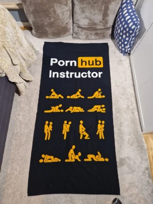 Svart filt med tryck cornhub - Rolig svart filt med texten 'cornhub Instructor' och illustrationer av olika positioner i gult och vitt. Perfekt som statement-piece i sovrummet eller loungen.Perfekt till stranden på sommaren Mjuk insida i grått med samma motiv i ljusare färg.