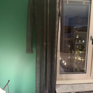 Lång mesh/nätklänning med nitar/strass. - Superfin mesh/nätklänning i mörkgrått med nitar/strass. Använd en gång. Minns ej var köpt, storlek 36/S, lapp bortklippt. 