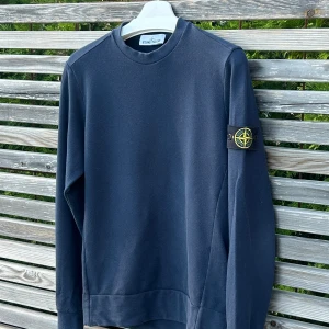 Mörkblå sweatshirt från Stone Island - Mörkblå sweatshirt från Stone Island med klassisk rund hals och ikonisk patch på vänster ärm. Tröjan har en clean look och är tillverkad i mjuk bomull. Sicket är 8,5/10 förutom sista bilden då den blivit missfärgad ⚠️