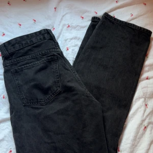 Svarta loose straight jeans Bershka - Svarta jeans från Bershka i loose straight-modell. Klassisk femficksdesign, hög midja och raka ben. Jeansen är tillverkade i denim och har snygga detaljer med nitar och dragkedja. 