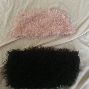 Fluffiga bandeau tubtoppar rosa & svart - Två fluffiga bandeau tubtoppar i rosa och svart. Båda är ärmlösa och har en mjuk, lurvig yta som ger en unik och trendig look. Perfekta för dig som vill sticka ut med en cool och lekfull stil. Säljes tillsammans. Använda 2 gånger men kommer inte till användning Storlek M men passar Xs också 💞